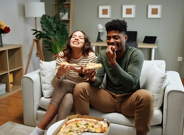 Couple souriant dégustant une pizza maison dans une ambiance conviviale et chaleureuse