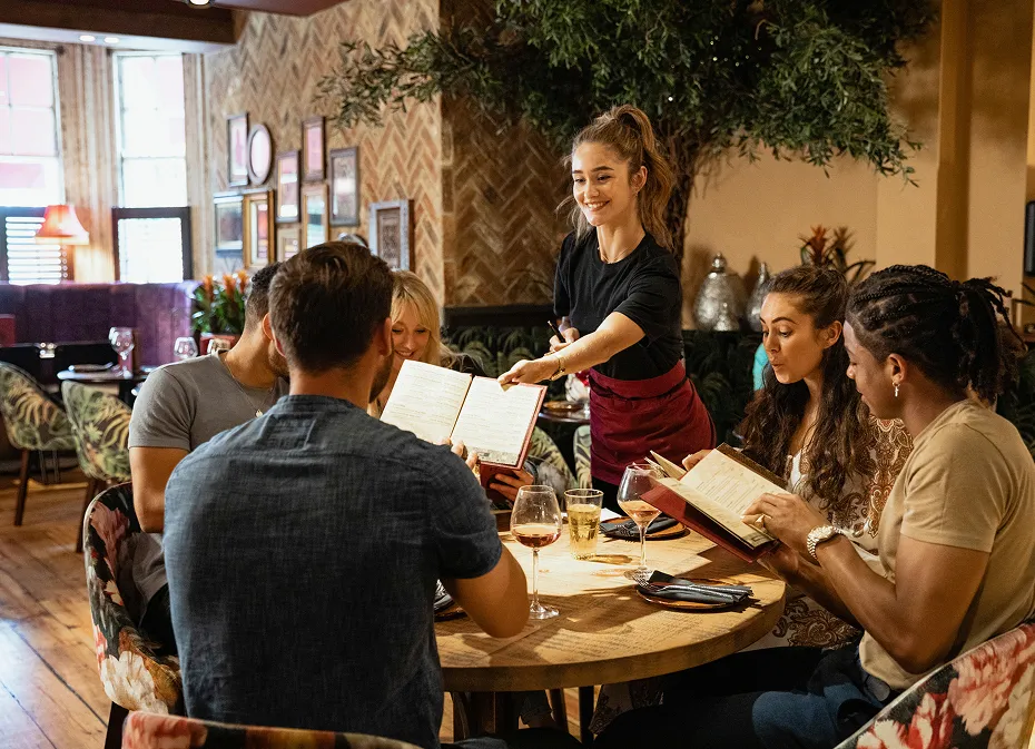 Groupe d’amis consultant les menus dans un restaurant convivial et chaleureux