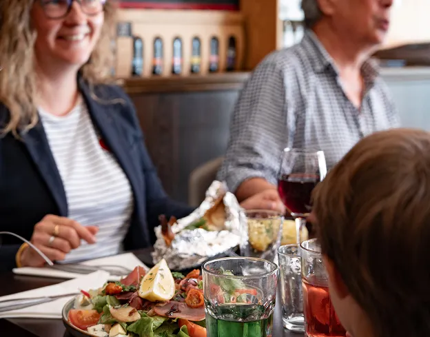 Groupe souriant partageant un repas convivial dans un restaurant familial