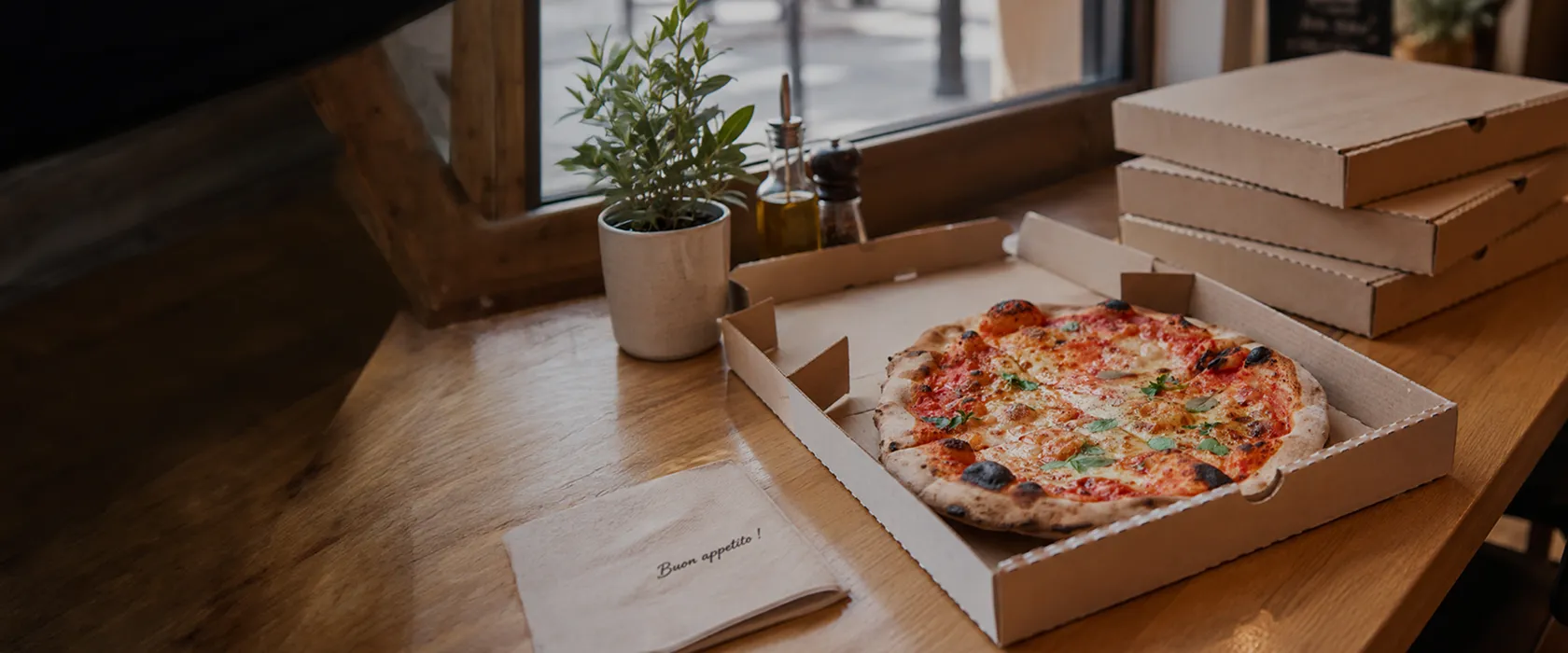 Pizza artisanale maison dans une boîte en carton sur une table en bois, ambiance chaleureuse